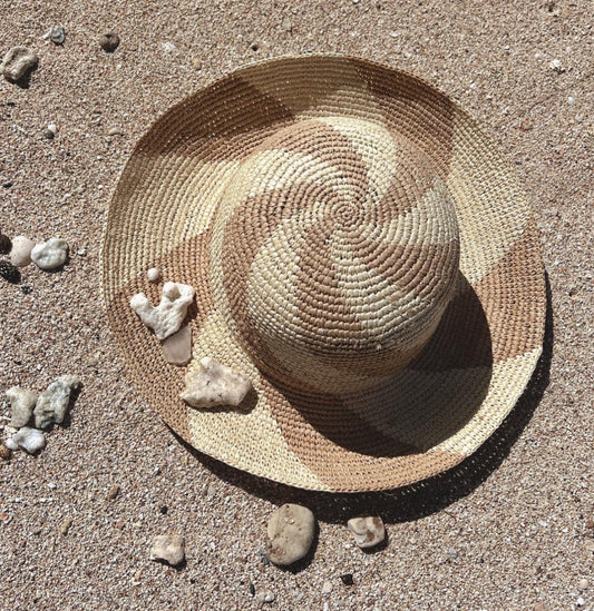 Woman wearing a raffia sun hat on the beach